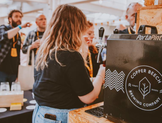 A woman pulling a pint of Copper Beech Beer.