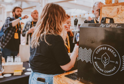 A woman pulling a pint of Copper Beech Beer.
